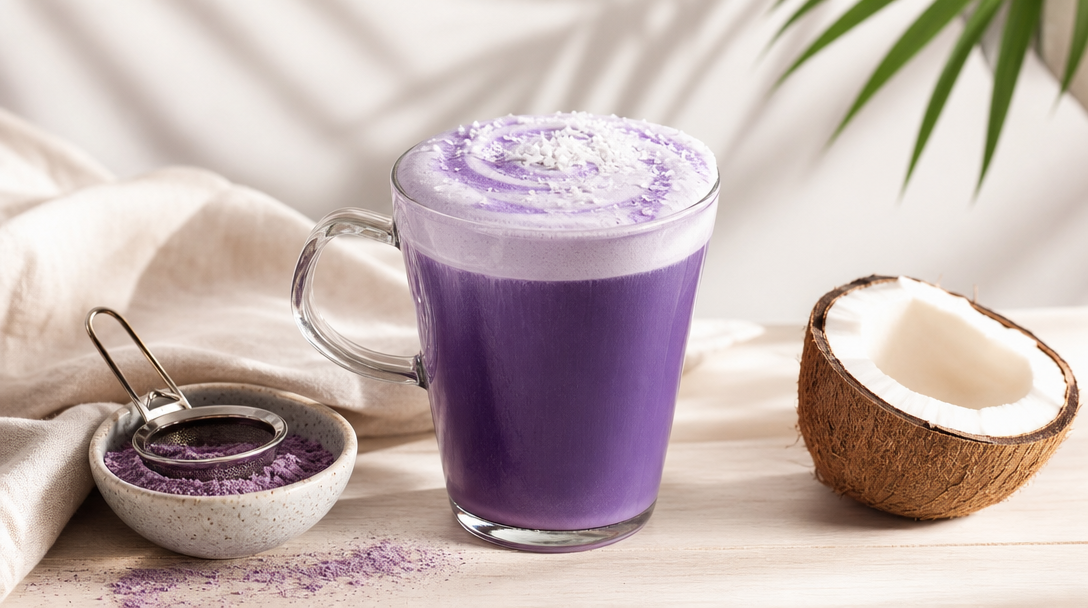 Ube coco latte violet dans une tasse en verre, avec noix de coco et poudre d'ube
