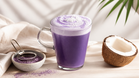 Ube coco latte violet dans une tasse en verre, avec noix de coco et poudre d'ube